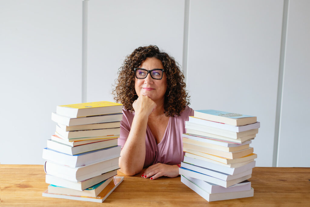 Mujer pensativa rodeada de libros